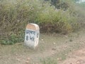 Kilometre Stone beside a rural Indian road with destination name Bengali word Bhalobasa written on it