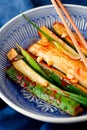 Kimchi of the Korean pickle cucumber.Marinated cucumbers with chili pepper, garlic, greens onion in blue plate close-up
