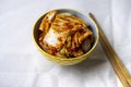 Kimchi in plate with chopsticks on light fabric