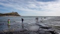 Kimmeridge Bay seascape with people on rocky outcrop into the sea and The Clavell Tower in Kimmeridge, Isle of Purbeck, Dorset, UK