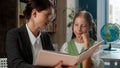 Kind adult Caucasian teacher professor woman female tutor reading story book storytelling explaining little girl school
