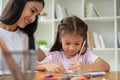 A kind Asian female teacher or babysitter is babysitting and teaching art to a young girl Royalty Free Stock Photo