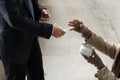 Kind businessman giving one dollar bill money to beggar or homeless guy