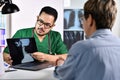 Asian male doctor in surgical uniform consulting and explaining female patient using laptop in examination room Royalty Free Stock Photo