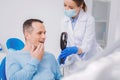 Kind dentist holding a mirror while a patient looking at his tooth