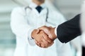 The kind of doctor you want to do business with. a doctor shaking hands with a businessman in a hospital. Royalty Free Stock Photo