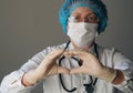 Kind elderly doctor in protective medical mask showing heart sign with hands in sterile gloves. The concept of a profession that Royalty Free Stock Photo