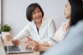A kind and friendly senior female boss is sharing her opinions and working with young colleagues Royalty Free Stock Photo