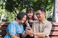 Kind and happy Asian senior grandparents enjoying looking at photos on their mobile phone in the park with their cute Royalty Free Stock Photo