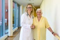 Kind Nurse Assisting Old Patient at the Hallway