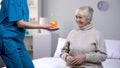 Kind nurse giving birthday cake to aged lonely woman, taking care in old age