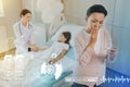 Kind nurse sitting with a patient and a worried mother