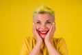 Kind positive mature woman with colored stylish yellow dyed hair, make up red lipstick on lips amazed looking with snow