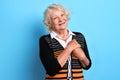 Kind positive old woman with hands on chest smiling, looking at the camera