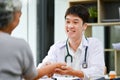 A kind Asian male doctor is checking a patient\'s pulse on a wrist while diagnosing the disease Royalty Free Stock Photo