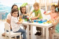 Kindergarten children playing toys with teacher in playroom at preschool. Education concept. Royalty Free Stock Photo