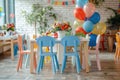 A kindergarten graduation setup with colorful chairs, balloons, and a festive table with flowers