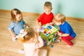 Kindergarten kids playing with educating toy on a wooden floor