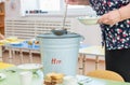 Kindergarten nurse puts soup on plates by scooping it with a ladle from a bucket