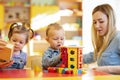 Kindergarten teacher playing with babies in nursery. Developmental toys for preschool.