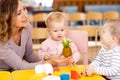Kindergarten teacher playing with nursery kids at table Royalty Free Stock Photo