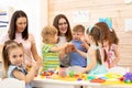 Kindergartener with kids group in classroom