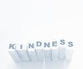 KINDNESS word made with wooden building blocks on neon aquamarine background