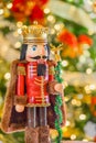 A king with a crown and cape  nutcracker stands  in front of  a  soft focused decorated Christmas tree Royalty Free Stock Photo