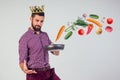 King of the kitchen with a golden crown on head chef holding a frying pan wizard man is cooking magic flying food salad