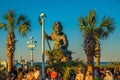 King Neptune Statue towering over beach visitors enjoying an outdoor concert