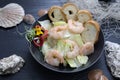 King prawn salad. Marine composition with a bowl of shrimp salad with iceberg lettuce, on a black table, top view. Royalty Free Stock Photo