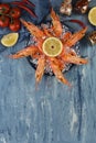 King size prawns on plate with ice and lemon on blue background.