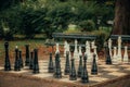 King size standing chess outside in a park. Black and white playing figures standing randomly on the checker board Royalty Free Stock Photo