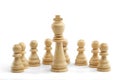 The king stands in front of a row of white pawns on a white background. White wooden chess pieces, close-up Royalty Free Stock Photo