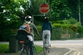British STOP road sign with family on bikes stopped and waiting to check if it is