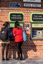 Students Withdrawing Money From An ATM Cash Point Machine