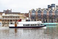 Tourist boat cruising along the River Thames passing the Riverside Walk promenade in Kingston upon Thames, England