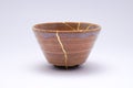 Beige Sake cup restored with the antique kintsugi real gold technique Royalty Free Stock Photo