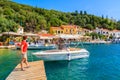 KIONI PORT, ITHACA ISLAND - SEP 19, 2014: young woman tourist standing on wooden jetty in Kioni port. Greece is very popular