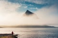 Kirkjufell mountain hidden in foggy over atlantic ocean and male tourist standing in summer at Iceland Royalty Free Stock Photo