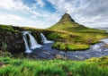 Kirkjufell mountain and waterfall in the Iceland. Natural landscape in the summer. Grass and river. Famous place.