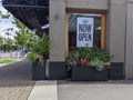 Kirkland, WA USA - circa June 2020: Side view of a Now Open sign on a restaurant window in downtown Kirkland during the