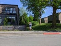 Kirkland, WA USA - circa May 2020: Street view of an adult walking down a residential sidewalk, carrying a bouquet of flowers as