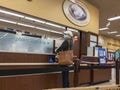 Kirkland, WA USA - circa October 2021: View of a woman in a baseball hat picking up a prescription at a pharmacy inside a Safeway Royalty Free Stock Photo