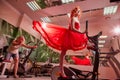 Kirov, Russia - May 30, 2019: Beautiful girl with makeup, red curly hair and a red dress in the gym. Spoort photoshoot