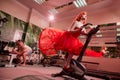 Kirov, Russia - May 30, 2019: Beautiful girl with makeup, red curly hair and a red dress in the gym. Spoort photoshoot