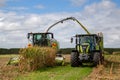 A Claas tractor and combine harvester working in a field in summer, Canterbury, New Zealand