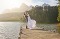 Kiss, dance and a married couple on a pier over a lake in nature with a forest in the background after a ceremony Royalty Free Stock Photo