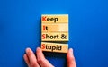 KISS keep it short and stupid symbol. Concept words KISS keep it short and stupid wooden blocks. Beautiful blue table, blue