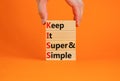 KISS keep it super and simple symbol. Concept words KISS keep it super and simple wooden blocks. Beautiful orange table, orange